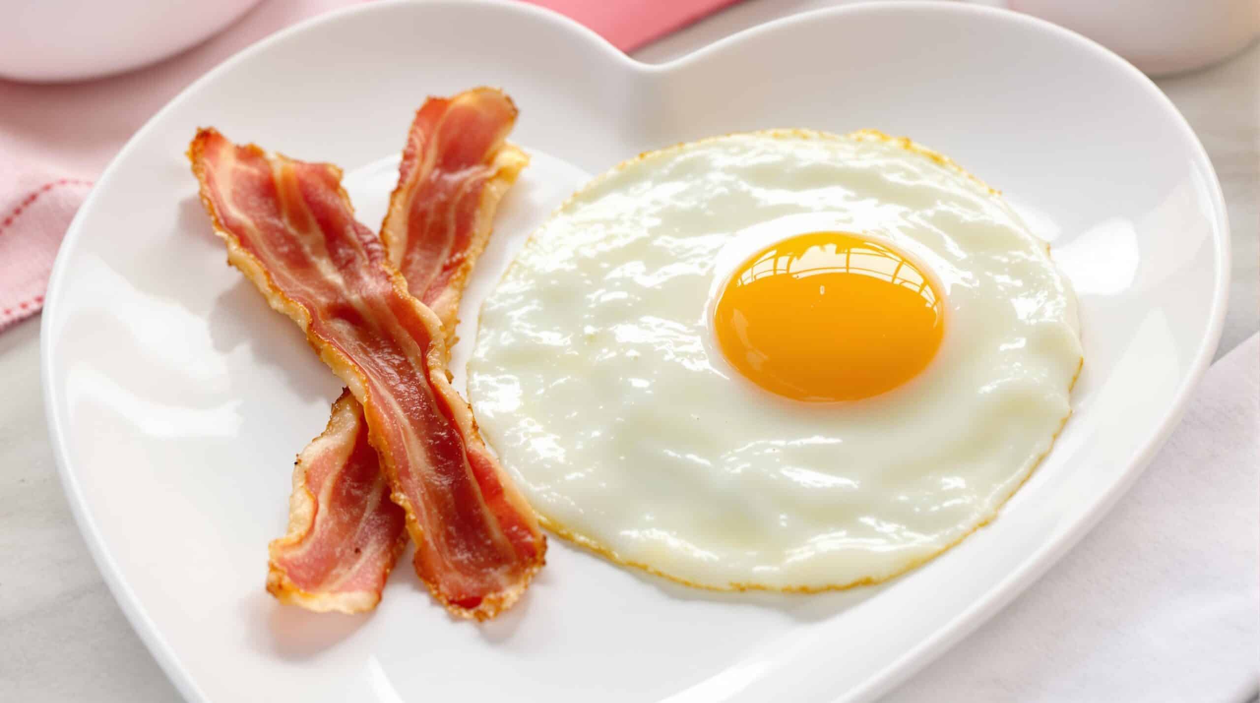 Huevos y bacon en un plato con forma de corazón
