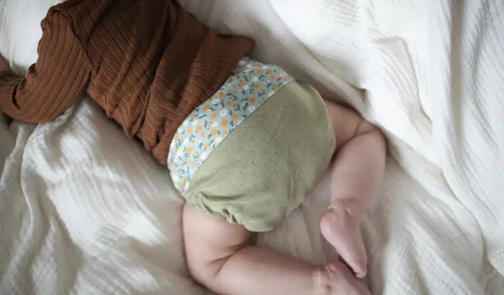 El cuerpo de un bebé fotografiado por detrás con un pañal de tela puesto.